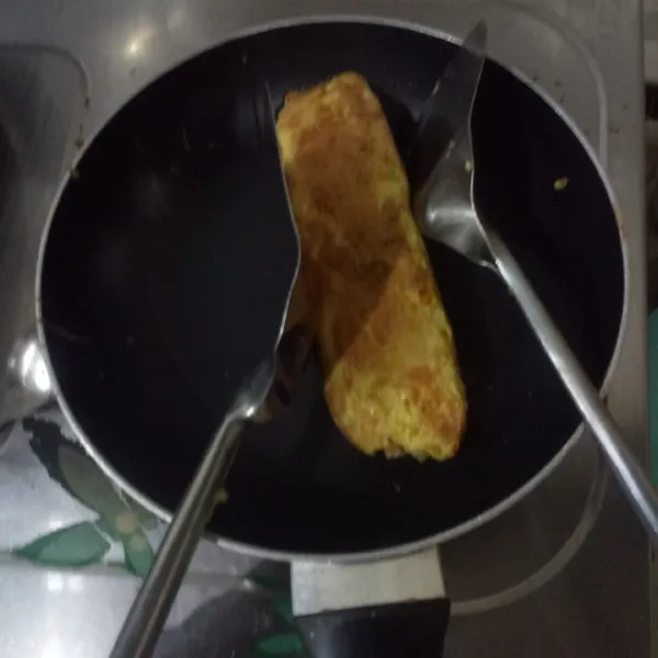 Gunakan 2 spatula untuk merapikan telur gulung, tekan-tekan agar padat, sambil dibolak-balik agar matang merata. Masak sampai kecoklatan,  Kemudian, angkat. Tunggu uap berkurang, iris tipis lalu sajikan.