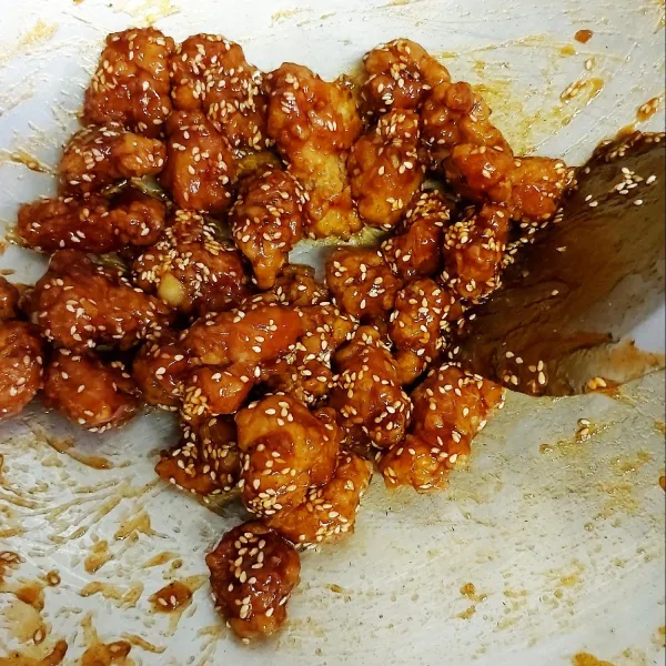 Masukkan ayam goreng bersama wijen, aduk rata, matikan api dan tuang di wadah saji.