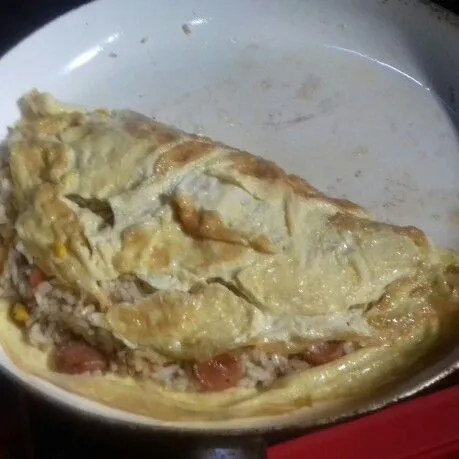 Lipat sisi yang lain hingga nasi tertutup omelette. Sajikan dengan sayur pelengkap.