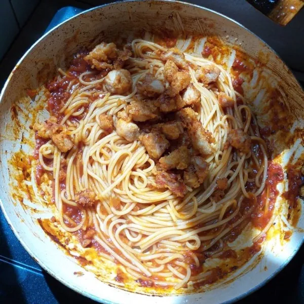 Setelah spagetti dan saus pasta diaduk merata, masukkan potongan spicy chicken yang sudah digoreng crispy, lalu aduk kembali