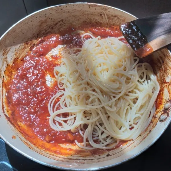 Setelah selesai direbus, masukkan spagetti yang sudah lembut ke saus pasta yang sedang dipanaskan. Aduk rata