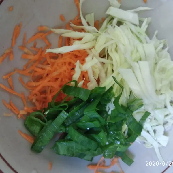 Parut wortel, iris halus kobis, iris kasar daun bawang kemudian masukkan dalam mangkok.