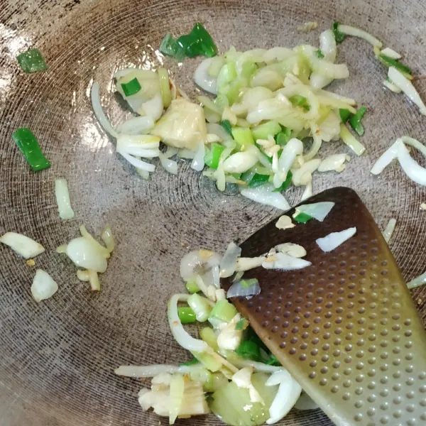 Tumis bawang bombay dan bawang putih. Jika sudah mulai layu, masukkan daun bawang dan jahe. Tumis hingga wangi.
