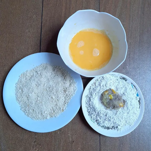 Gulingkan adonan yang sudah dibentuk ke tepung terigu. Celup ke kocokan telur. Gulingkan ke tepung roti.