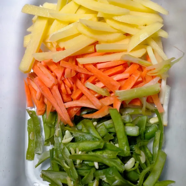 Potong-potong buncis, wortel, kentang dan daun bawang secara memanjang.