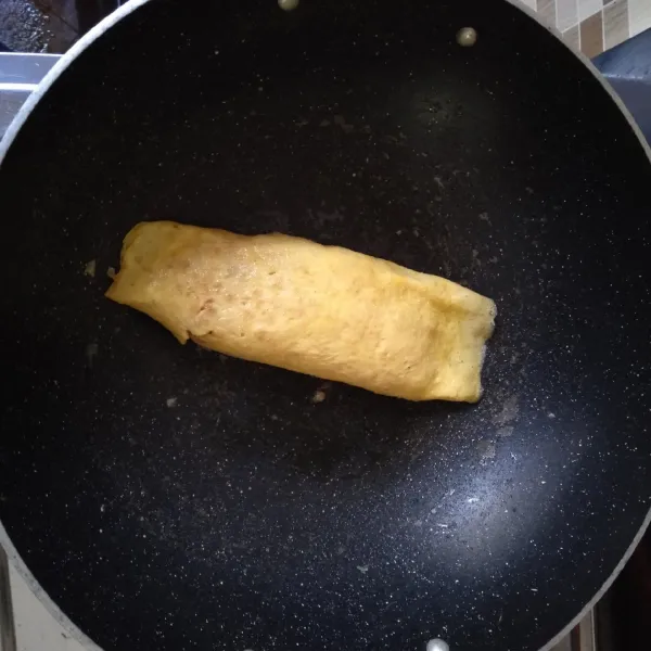 Lipat sisi kanan dan kiri telur ke arah nasi,  hati-hati saat melipat. Tekan-tekan agar tidak berubah bentuk.