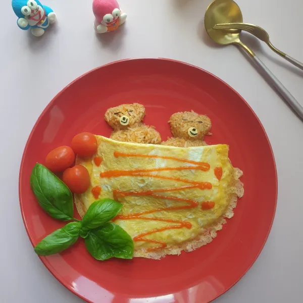 Bentuk nasi goreng dengan cetakan/ bungkus nasi goreng dengan omelette. Sajikan dengan saus tomat, tomat cherry dan salad kesukaan Anda.