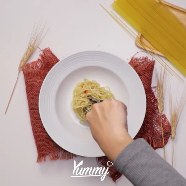 Sajikan Spaghetti Jamur Aglio Olio dengan taburan chilli flakes dan keju parmesan.