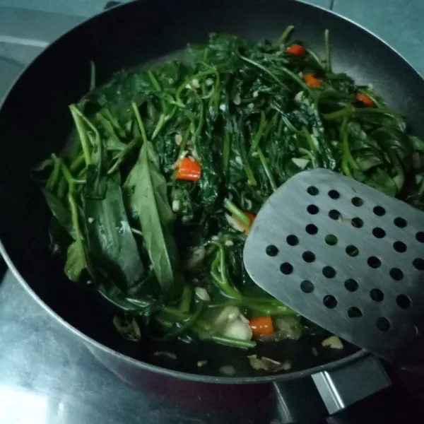 Masukkan kangkung, beri sedikit air, dan tunggu hingga agak layu.