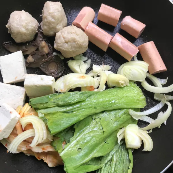 Potong-potong bawang putih, bawang bombay, sosis, tahu putih, dan bakso. Lalu tata kedalam teflon dengan jamur, pakcoy, dan kimchi.