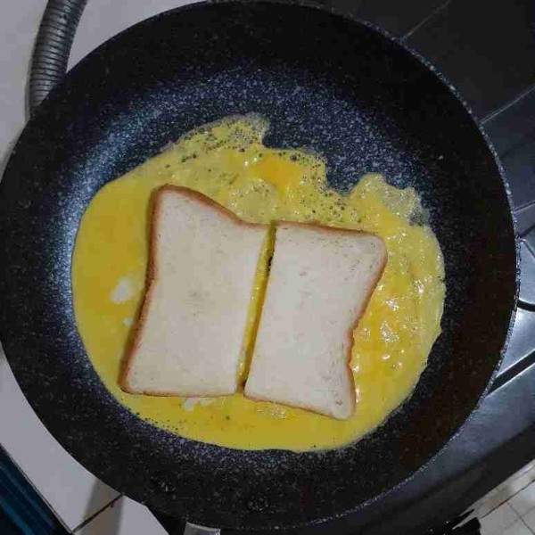 Taruh potongan roti tawar di atas telur, beri jarak antara rotinya.