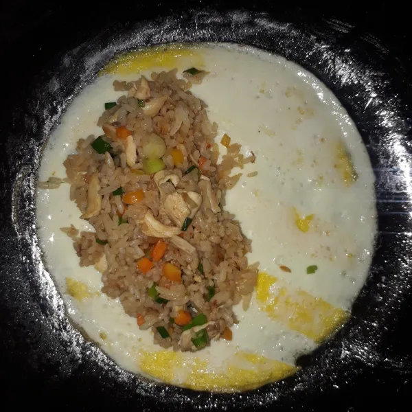 Letakkan nasi goreng disetengah bagian omelet telur.