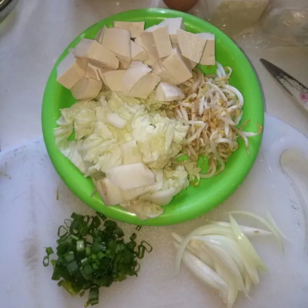 Cuci bersih tauge, sawi putih dan daun bawang. Iris halus bawang bombay, daun bawang, sawi putih. Tahu dipotong dadu.
