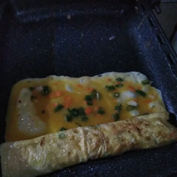 Setelah itu, tuang 1/4 adonan lagi ke samping yang tidak digulung dan masak sampai 1/2 matang lalu gulung.