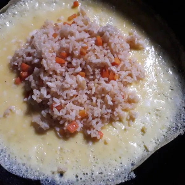 Tunggu hingga permukaan sedikit mengering, lalu letakkan secukupnya nasi goreng diatasnya, lalu lipat perlahan.