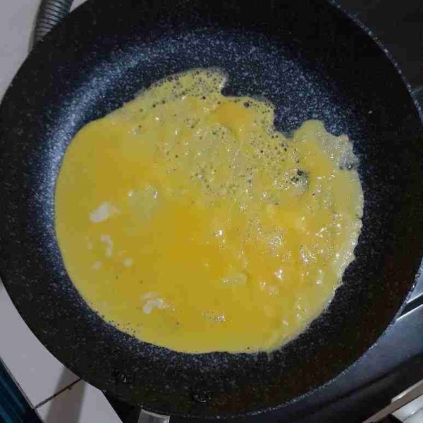 Tuang kocokan telur dalam teflon. Ratakan.