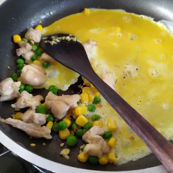 Tambahkan sedikit margarin di tepi wajan, tuang telor kocok bikin urak arik.