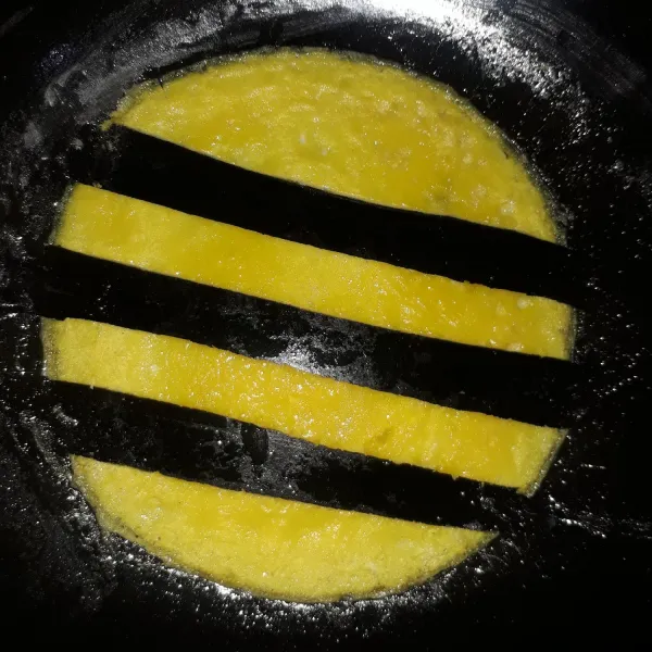 Pisahkan putih dan kuning telur. Tambahkan sedikit garam lalu kocok lepas masing-masing bagian telur. Goreng kuning telur sampai matang. Potong selang-seling menggunakan spatula.