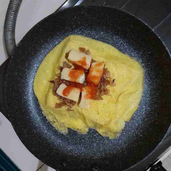 Masukkan tumisan sosis diatas telur beserta potongan keju mozzarella dan saus bangkongnya.