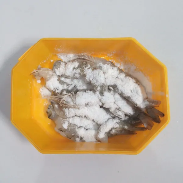 Kupas kulit udang. Cuci bersih. Kerat-kerat perutnya. Kemudian tekan punggungnya. Taburi dengan tepung maizena.