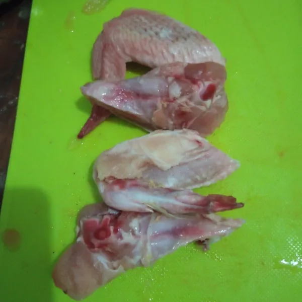 Cuci bersih sayap ayam kemudian potong menjadi dua bagian.