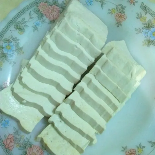 Belah tahu menjadi 2, kemudian iris tipis sekitar 1 cm.