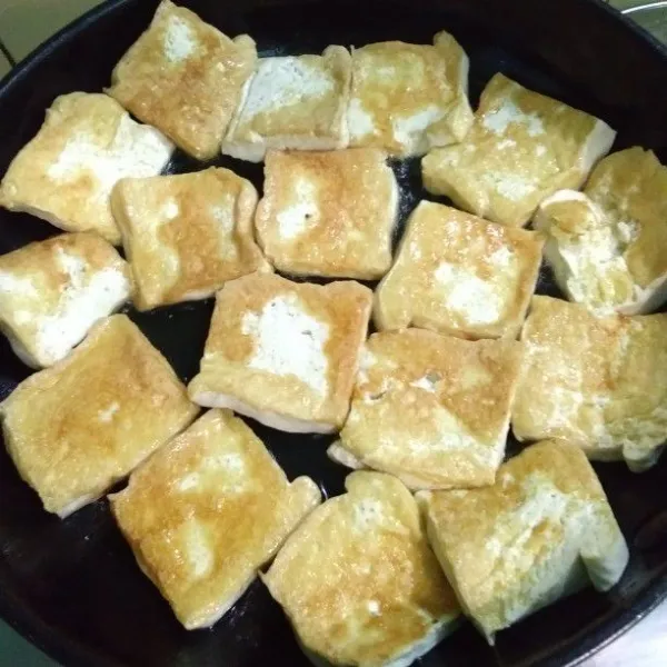 Goreng tahu tidak terlalu kering kemudian balik, lakukan hal yang sama pada sisi sebaliknya. Angkat tiriskan.