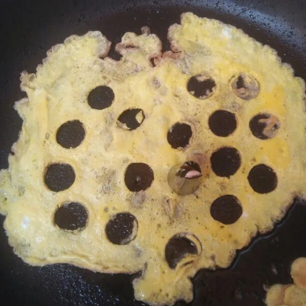 Panaskan teflon lalu dadar telur nya setelah setengah matang lubangi dadar telur dengan spluit.