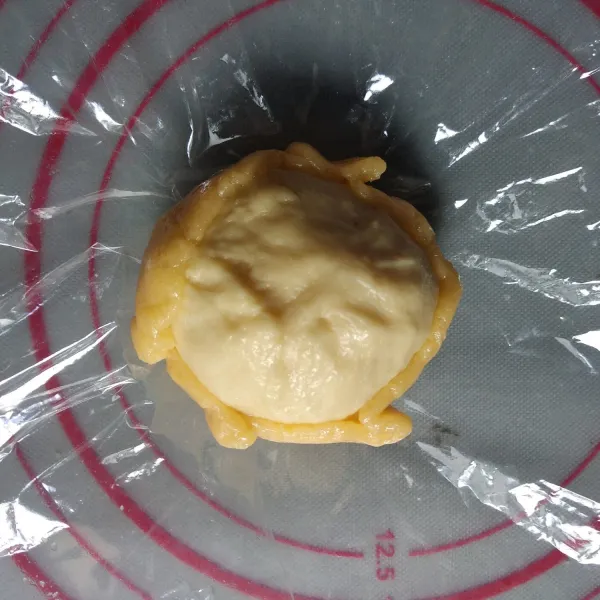 Bulatkan adonan roti, letakkan di tengah-tengah adonan topping yang sudah digilas kemudian bungkus.
