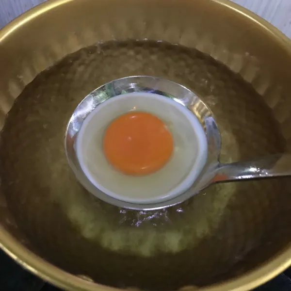 Tuang telur di atas sendok sayur, lalu letakkan di atas air yang mendidih hingga putih telur padat.