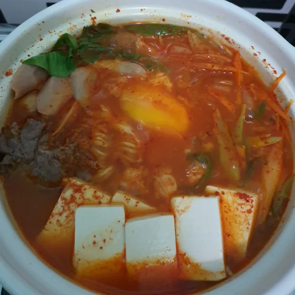 Setelah setengah matang, masukkan telur kedalam pot, lalu masak sebentar hingga matang, lalu taburi minyak wijen di atasnya.