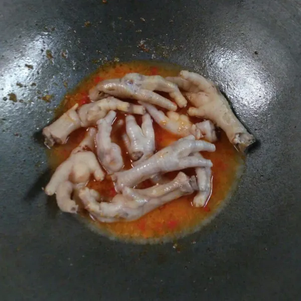 Tuang air rebusan ceker, masukkan ceker, aduk. Biarkan mendidih.