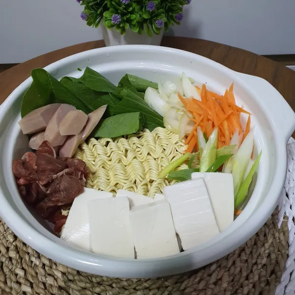 Tata semua bahan (Mie, pokcoy, daging sapi, wortel, sosis, tahu sutra, daun bawang, dan bawang bombay) dalam Pot.
