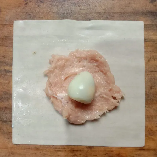 Ambil 1 lembar pangsit, letakkan 1 sdm adonan ayam pipihkan. Letakkan telur puyuh diatasnya.