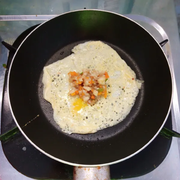 Panaskan teflon. Ambil 1 sendok sayur telur. Tuang di atas teflon. Masak setengah matang. Beri isian di tengahnya.