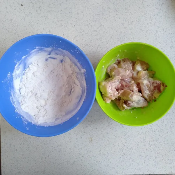 Masukkan potongan daging ayam ke dalam tepung basah, kemudian pindahkan ke tepung kering. Baluri semua bagian daging dengan tepung kering.