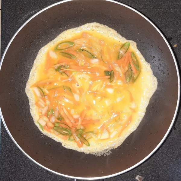 Masukkan 1 sendok sayur adonan telur ke dalam wajan. Biarkan hingga setengah matang.