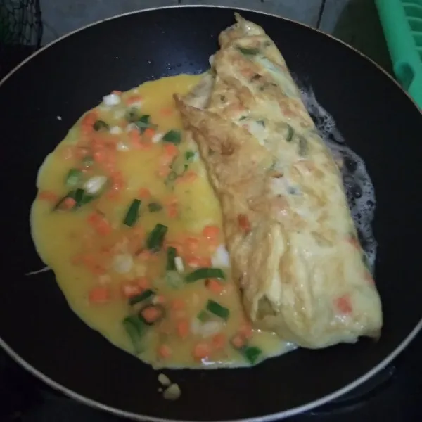 Gulung sebagian telur dadar sambil ditekan, tuang lagi adonan telur dadar menyambung dengan bagian yang tidak dilipat. lipat lagi dan lakukan hingga adonan habis.