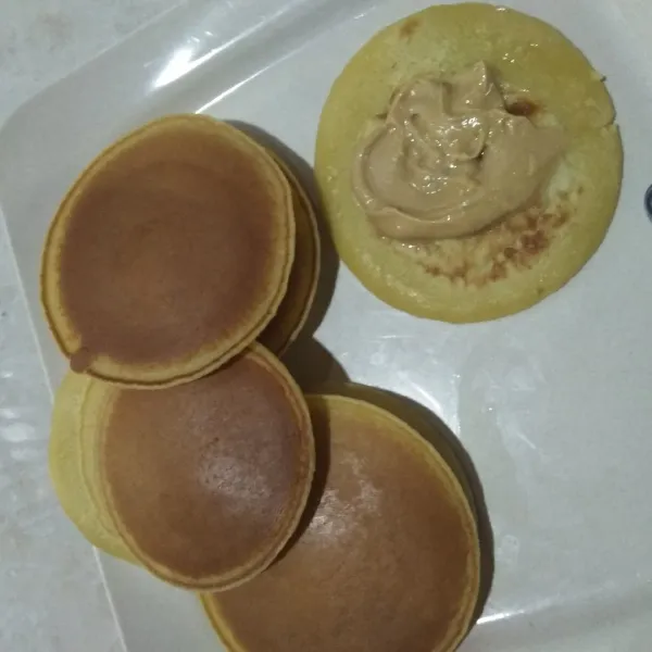 Ambil 2 buah pancake dorayaki, lalu beri selai pada sisi bagian dalam lalu tumpuk dan siap dinikmati.