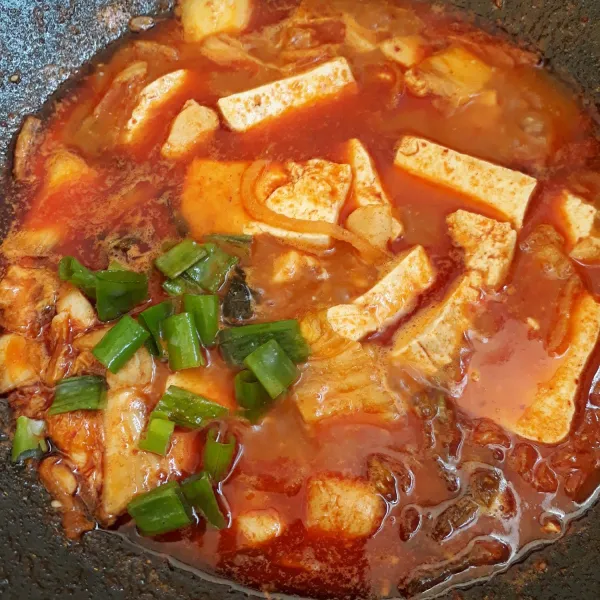 Masukkan tahu, biarkan air menyerap. Terakhir masukkan daun bawang, sajikan segera.