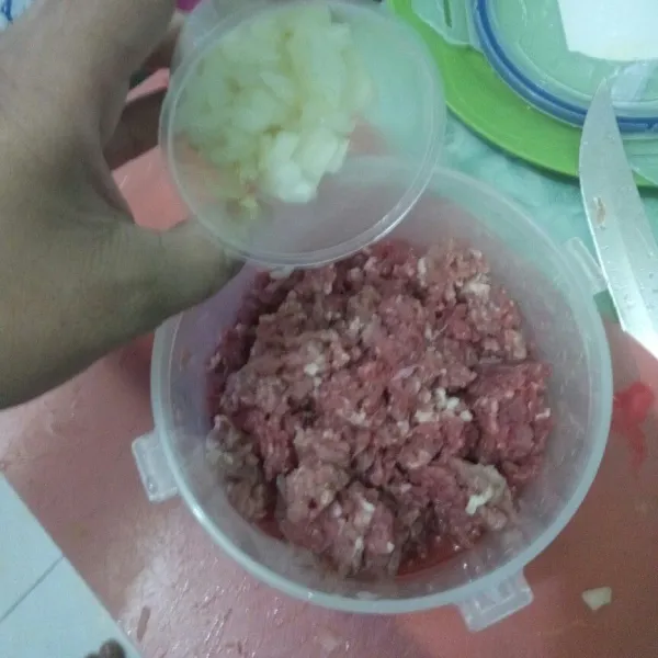 Masukkan bawang bombay ke dalam daging cincang, lalu aduk rata.