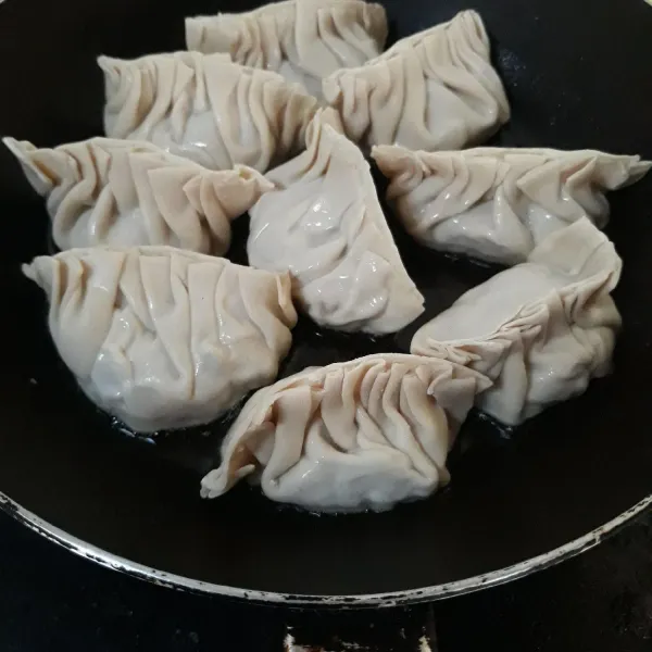 Panaskan sedikit minyak. Tata gyoza dan goreng hingga alasnya berwarna coklat.