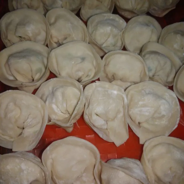 Celupkan jari telunjuk ke dalam air, basahi pinggiran kulit dan lipat hingga menjadi setengah lingkaran. Pegang kedua sisi pangsit, temukan ketengah hingga membentuk lingkaran. Rekatkan kembali dengan air, lakukan hingga habis. Untuk pangsit yang tidak dimasak, bisa disimpan di tempat yang kering dan tertutup. Simpan dalam kulkas.