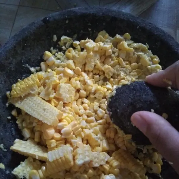Tambahkan serutan jagung, lalu uleg kasar sebagian, sebagian lagi biarkan utuh.