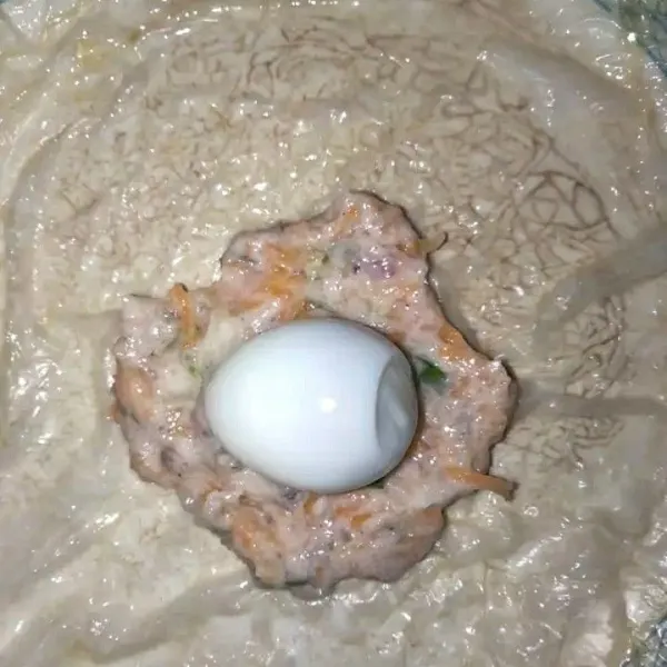 Pipihkan kulit tahu yang sudah direndam. Letakkan adonan ekado dan beri telur puyuh di tengahnya.