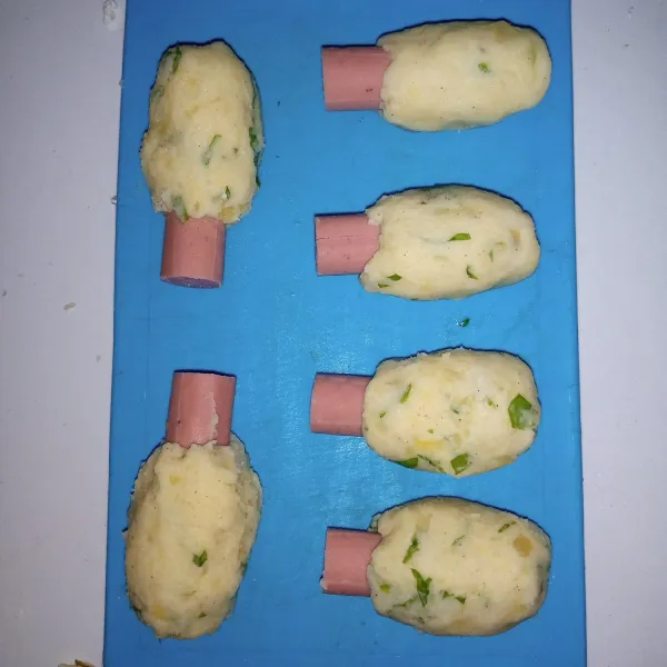 Bungkus bagian atas sosis dengan adonan kentang. Sisakan bagian yang sudah di kerat.