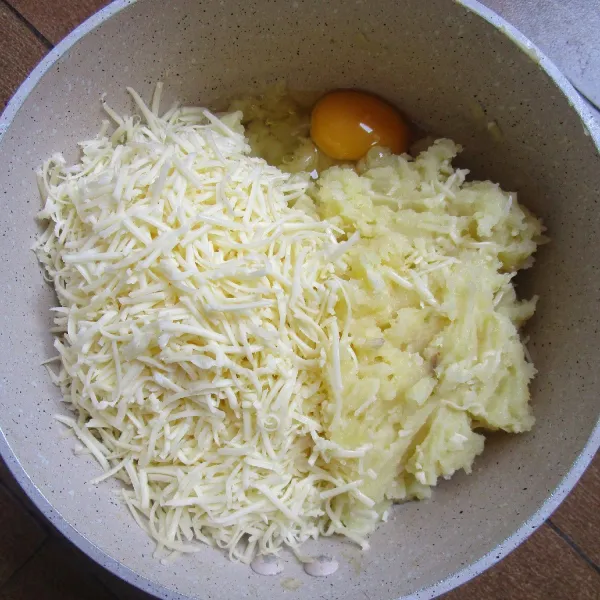 Campur kentang yang sudah dikukus dan dihaluskan dengan garpu, keju cheddar parut, telur, lada bubuk (sesuai selera) dan merica bubuk (sesuai selera). Aduk rata. Sisihkan.