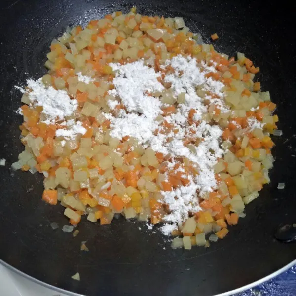 Setelah wortel dan kentang lunak dan air menyusut, masukkan tepung terigu. Aduk rata.