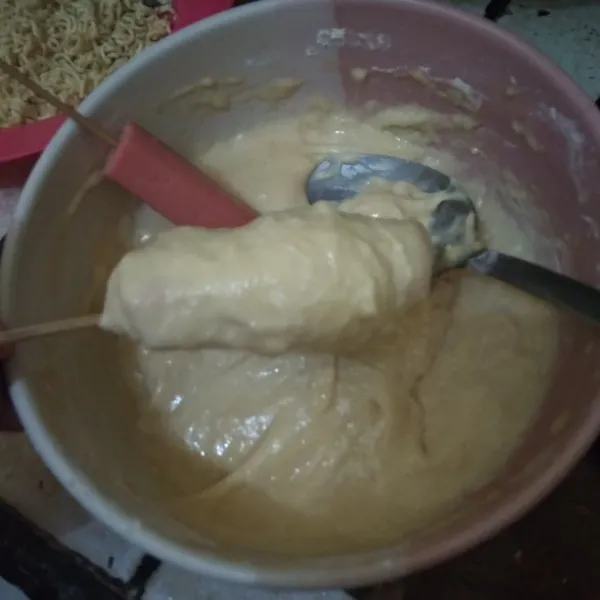 Ambil satu buah sosis. Balur dengan adonan tepung hingga rata.