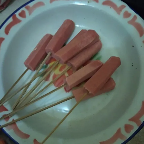 Potong sosis menjadi 2 bagian lalu tusukan pada tusuk sate.